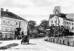 Ein Schwarz-Weiß-Foto einer Straße mit Gebäuden und einem Traktor